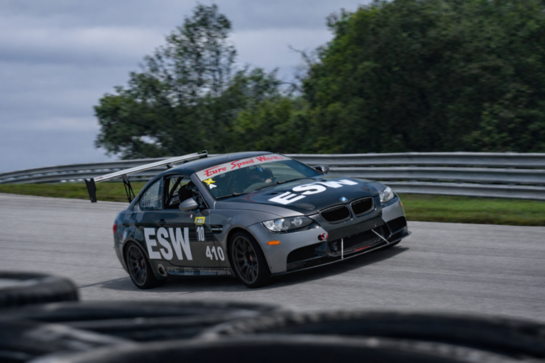 Closeup of a grey high performance vehicle with "ESW" painted on its side driving on the Ozark International HPDE track.